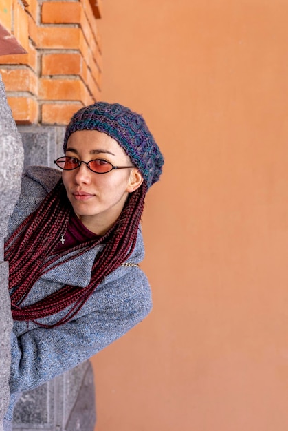 Portret van een vrouw die achter de muur kijkt.