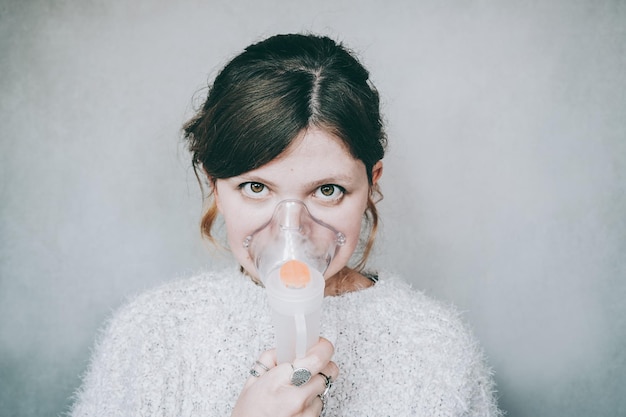 Foto portret van een vrouw die ademt met een zuurstofmasker tegen de muur