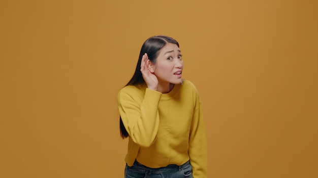 Portret van een vrouw die discussie in de studio afluistert, luistert naar gesprekken en roddels. Persoon die nieuwsgierig nieuws en geheim ontdekt, geschokt is en oor voor de camera blootlegt.