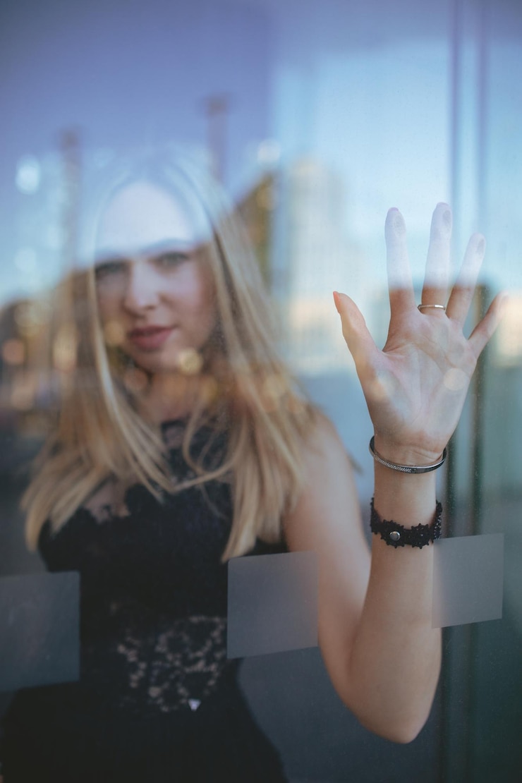 Foto portret van een vrouw die door een glazen raam kijkt