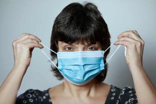 Portret van een vrouw die een gezichtsmasker draagt. Griepepidemie, coronavirus, stofallergie, bescherming tegen virussen.