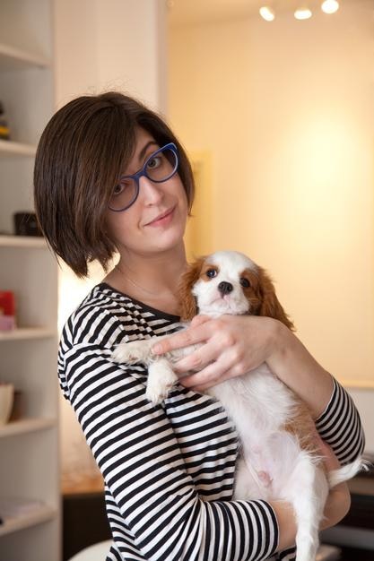 Portret van een vrouw die een hond vasthoudt terwijl ze thuis staat