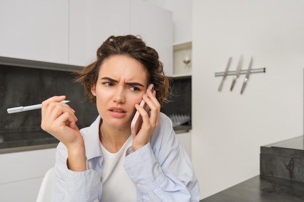 Portret van een vrouw die een ingewikkeld gesprek heeft terwijl ze een smartphone vasthoudt en fronst met gefrustreerde confus