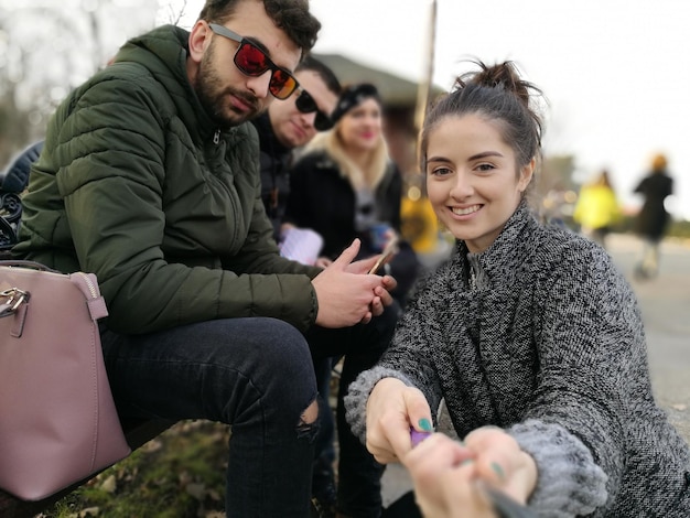 Portret van een vrouw die een monopod vasthoudt met vrienden die buiten zitten