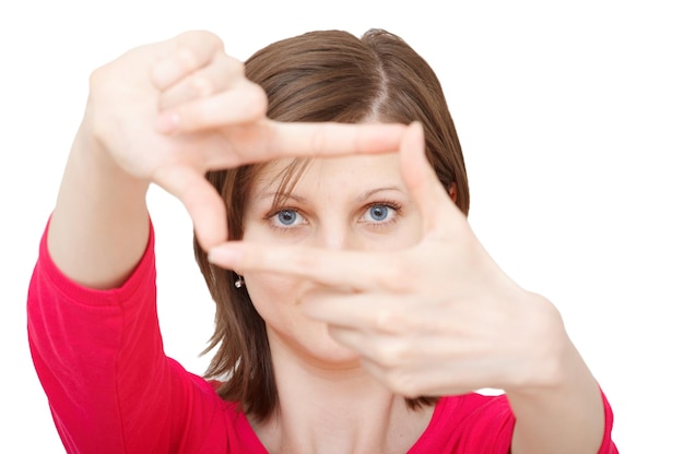 Portret van een vrouw die een vingerframe maakt terwijl ze tegen een witte achtergrond staat