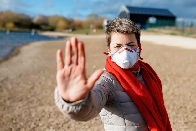 Portret van een vrouw die een wit en rood gezichtsmasker draagt, met stop buitenshuis