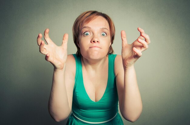 Foto portret van een vrouw die gebaren maakt terwijl ze tegen de muur staat