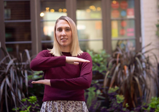 Foto portret van een vrouw die gebaren maakt terwijl ze tegen planten staat