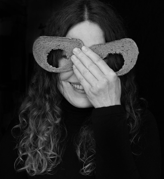Foto portret van een vrouw die haar ogen bedekt met stukjes brood op een zwarte achtergrond