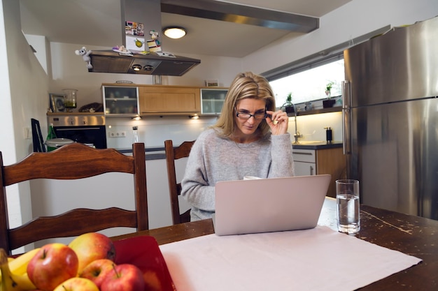 Portret van een vrouw die in de keuken zit