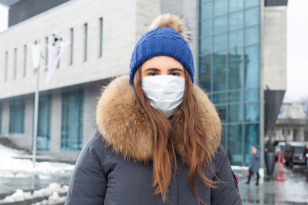 Portret van een vrouw die in de winter over straat loopt met een beschermend masker ter bescherming tegen infectieziekten Bescherming tegen verkoudheid griep luchtvervuiling Gezondheidsconcept