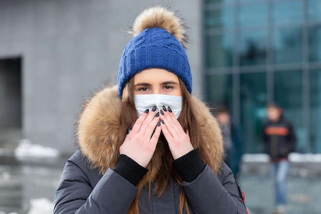 Portret van een vrouw die in de winter over straat loopt met een beschermend masker ter bescherming tegen infectieziekten bescherming tegen verkoudheid griep luchtvervuiling gezondheidsconcept