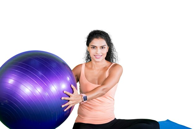 Portret van een vrouw die met een fitnessbal oefent op een witte achtergrond