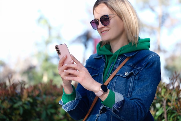 Portret van een vrouw die naar het scherm van een smartphone kijkt en een gelukkige vrouw glimlacht met behulp van