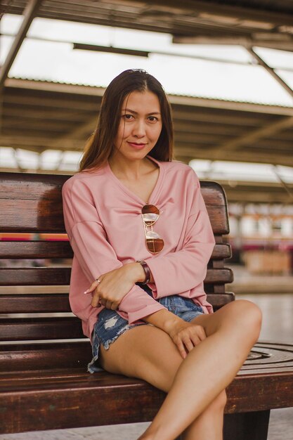Portret van een vrouw die op een bank op het perron van een treinstation zit