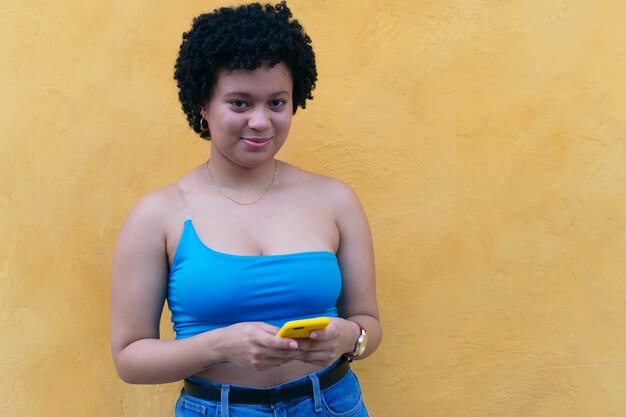 Portret van een vrouw die op straat loopt en een mobiele telefoon vasthoudt, glimlachend.