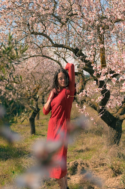 Portret van een vrouw die poseert met een amandelboom en een lenteomgeving