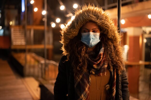 Portret van een vrouw die's nachts een masker draagt in de stad in 2020