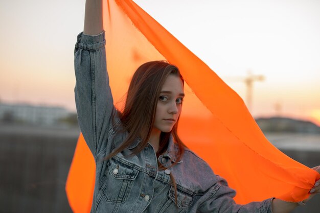 Portret van een vrouw die tegen de oranje hemel staat