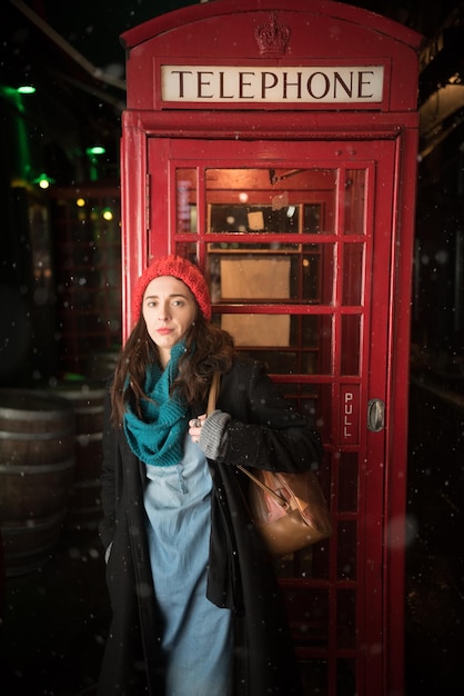 Portret van een vrouw die tegen een telefooncel staat