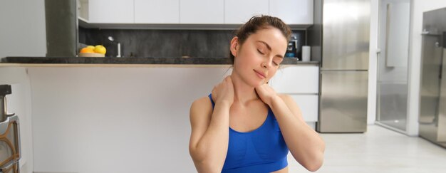 Foto portret van een vrouw die thuis traint, doet trainingsoefeningen en strekt haar nekopwarming uit voordat ze gaat fitnessen