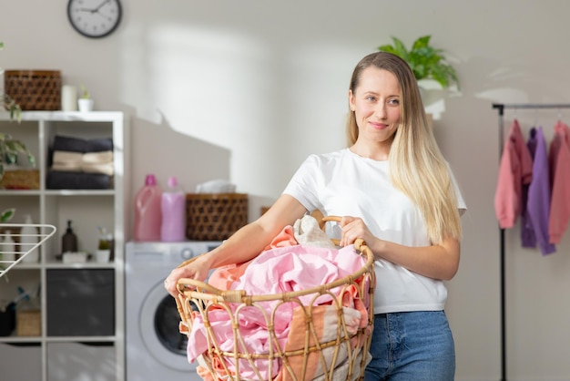 Portret van een vrouw die thuis werkt, houdt een rieten mand vast met kleren om te wassen