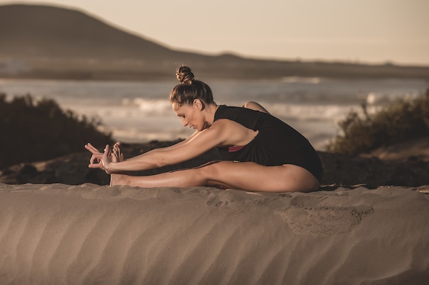 Portret van een vrouw die yoga op het strand doet