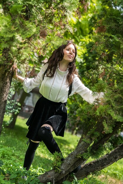 Portret van een vrouw draagt een witte blouse en een stijlvolle zwarte rok in de buurt van een groene boom, stadspark