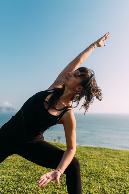 Portret van een vrouw gekleed in het zwart buiten beoefent yoga. Kopieer ruimte