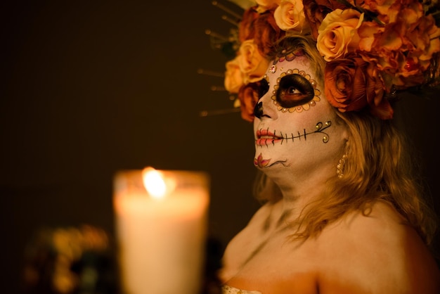 Portret van een vrouw in catrina make-up die een trouwjurk draagt Kaars en schedel vervaagd op de voorgrond