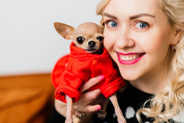 Portret van een vrouw in donkere kleren met een kleine hond samen over lichte Kerstmisachtergrond