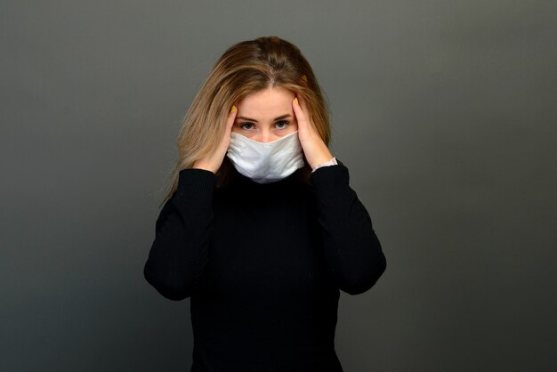 Portret van een vrouw in een medisch masker, dat een rubberen handschoen aantrekt