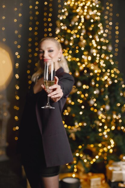 Portret van een vrouw in elegante avondjurk die bij de kerstboom staat