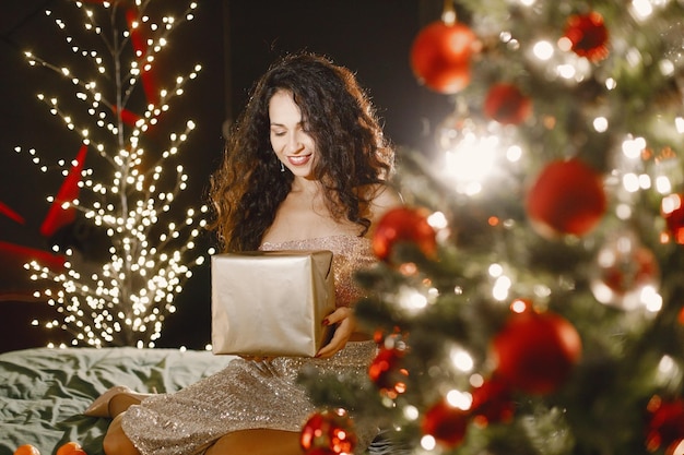 Portret van een vrouw in elegante avondjurk zittend op een bed