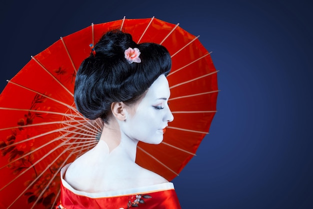 Portret van een vrouw in rode kimono met uitzicht op de paraplu van achteren