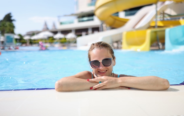 Portret van een vrouw in zonnebril in waterpark in zwembad