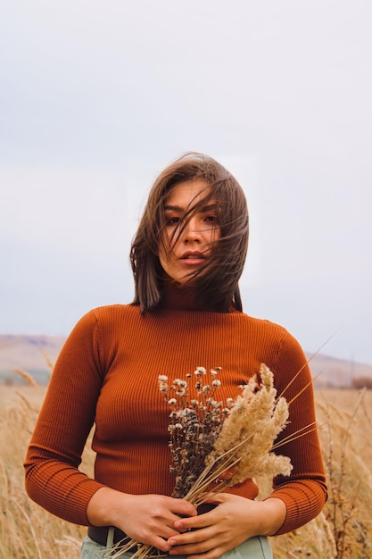 Portret van een vrouw met bloemen in haar handen op de achtergrond van het veld