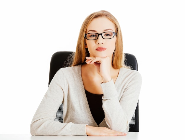 Portret van een vrouw met de hand op de kin die tegen een witte achtergrond zit