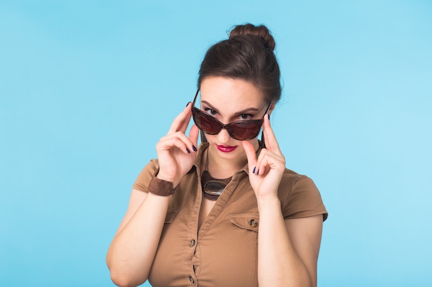 Portret van een vrouw met een bril op een blauwe muur.