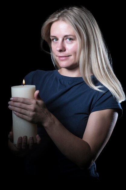 Portret van een vrouw met een dikke brandende kaars in haar hand geïsoleerd op een witte achtergrond