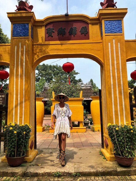 Foto portret van een vrouw met een hoed die bij de tempel staat