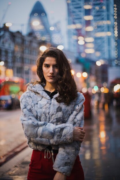 Portret van een vrouw met een jas die op straat staat in de stad