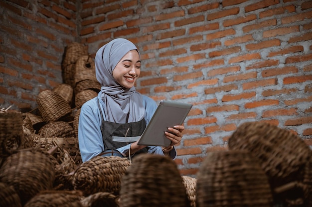 Foto portret van een vrouw met een laptop terwijl ze tegen een bakstenen muur staat