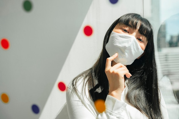 Portret van een vrouw met een masker die thuis bij het raam zit