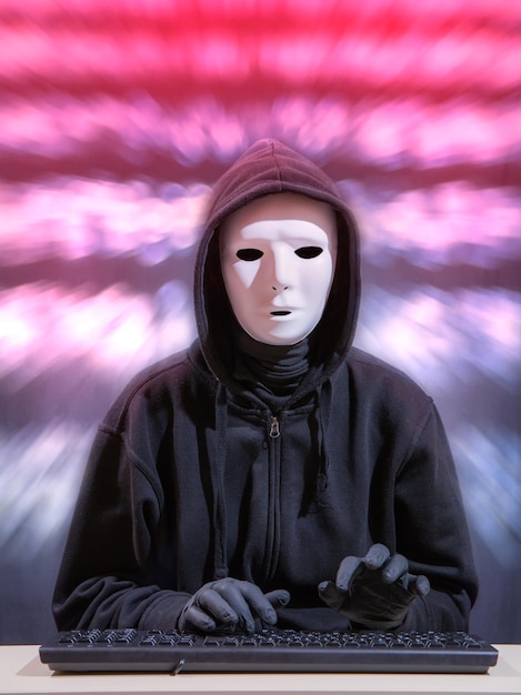 Portret van een vrouw met een masker terwijl ze op een toetsenbord schrijft tegen een wazige achtergrond