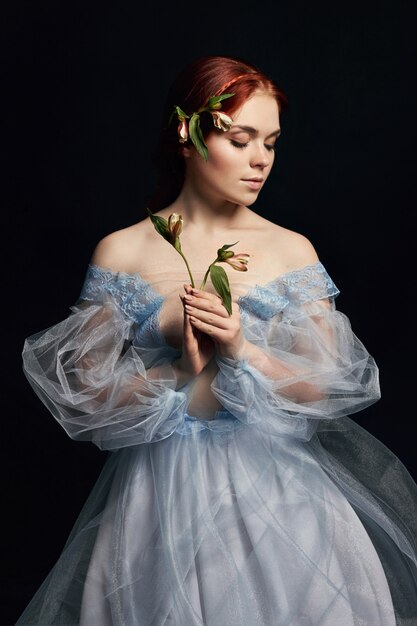 Portret van een vrouw met een middeleeuwse bloem in haar handen op de omslag van het boek. Perfecte natuurlijke schoonheid van een meisje met lang haar