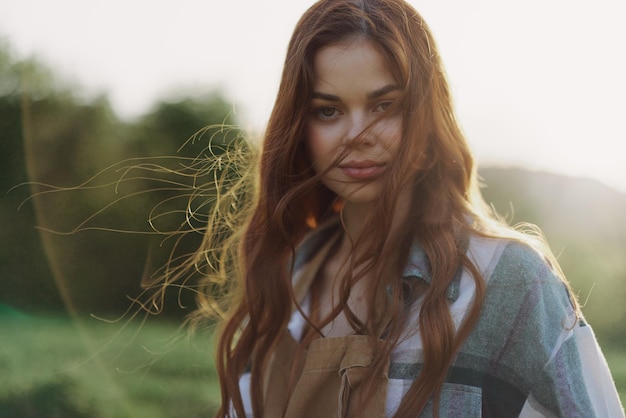 Portret van een vrouw met een mooie glimlach en rechte tanden op een zomerse dag in de zonsondergang met wuivend krullend haar