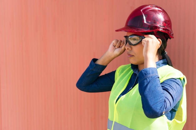 Portret van een vrouw met een veiligheidsbril en een veiligheidshelm in een fabriek