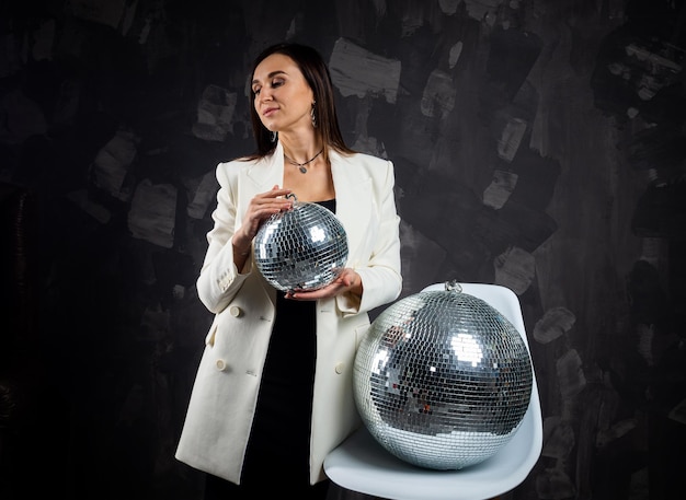 Foto portret van een vrouw met een zilveren disco bal genomen in een fotostudio het concept van het feest