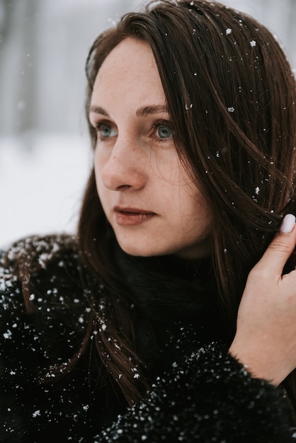 Portret van een vrouw op de achtergrond van een besneeuwd bos